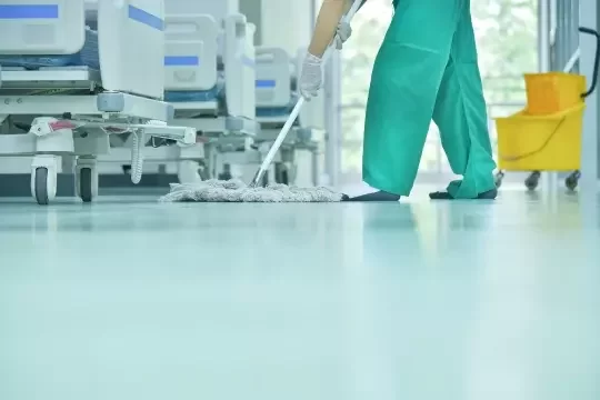 A cleaning operative mops a hospital ward floor.