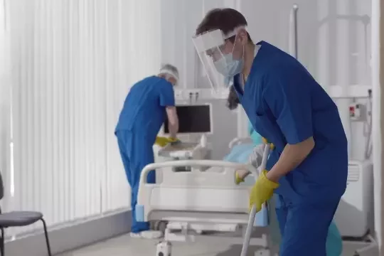 Cleaning operatives disinfecting a patient ward in a hospital.